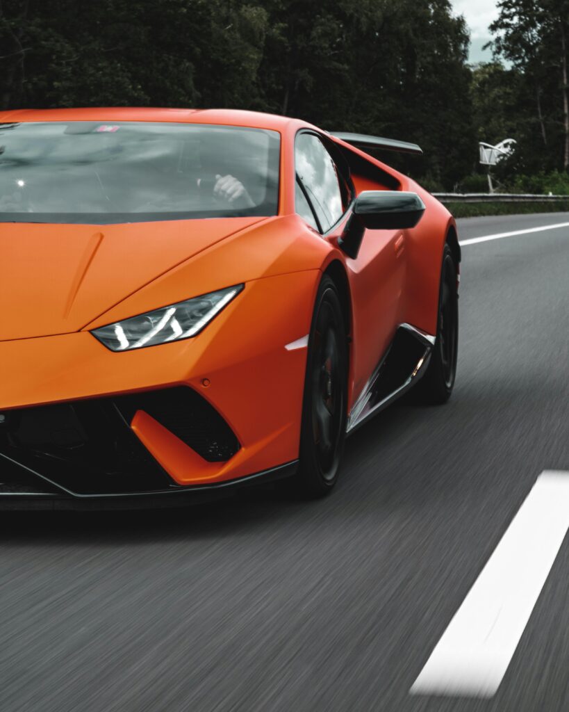 pexels-photo-11095885-11095885 Vibrant orange Lamborghini Huracan speeding on an open highway, showcasing luxury and performance.