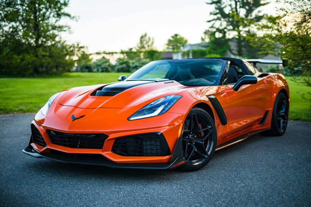 pexels-photo-3972755-3972755 A sleek orange convertible sports car elegantly parked on a scenic outdoor road.